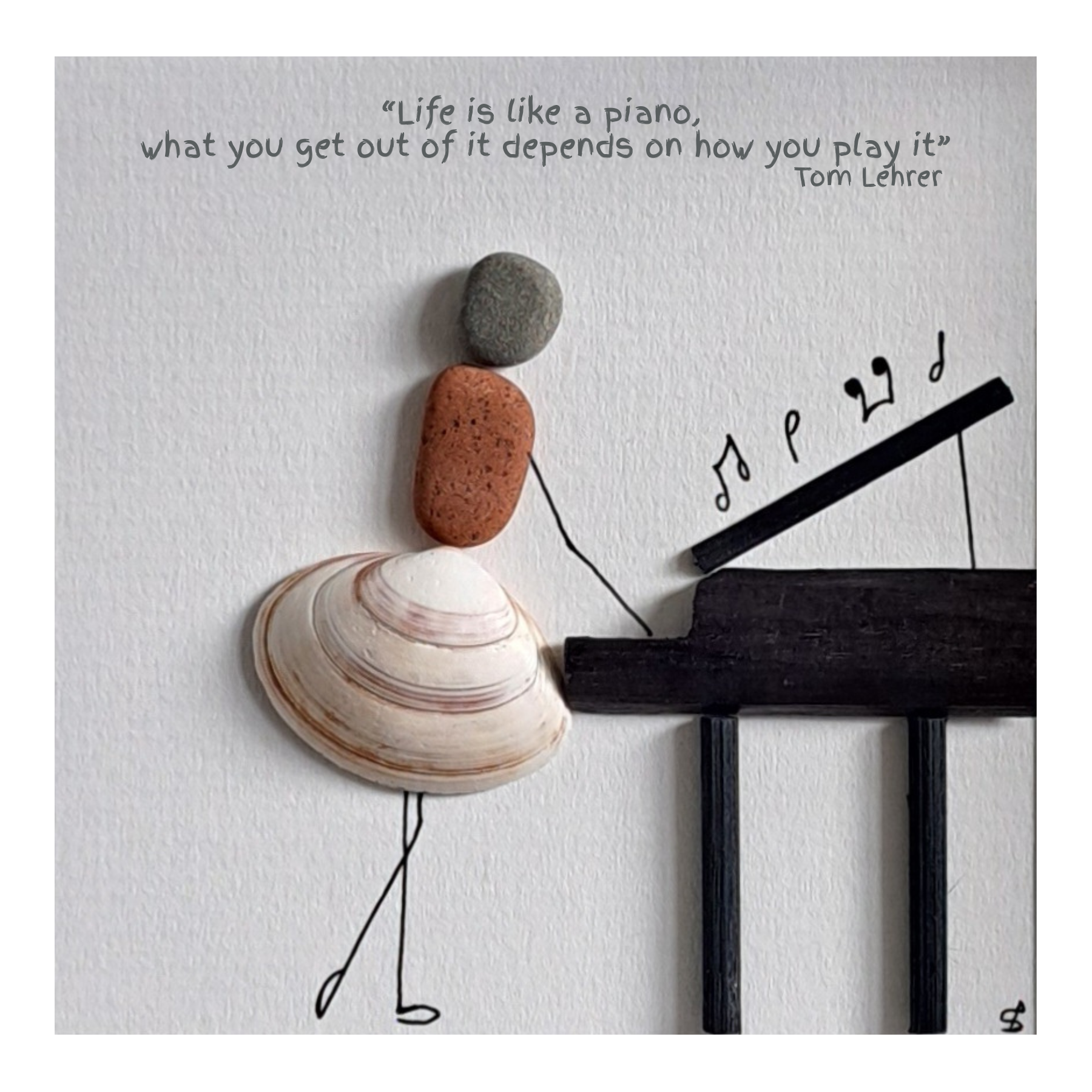 Decorative arrangement of beach pebbles and a shell depicting a girl playing the piano created from driftwood on a textured surface with a quote about life.